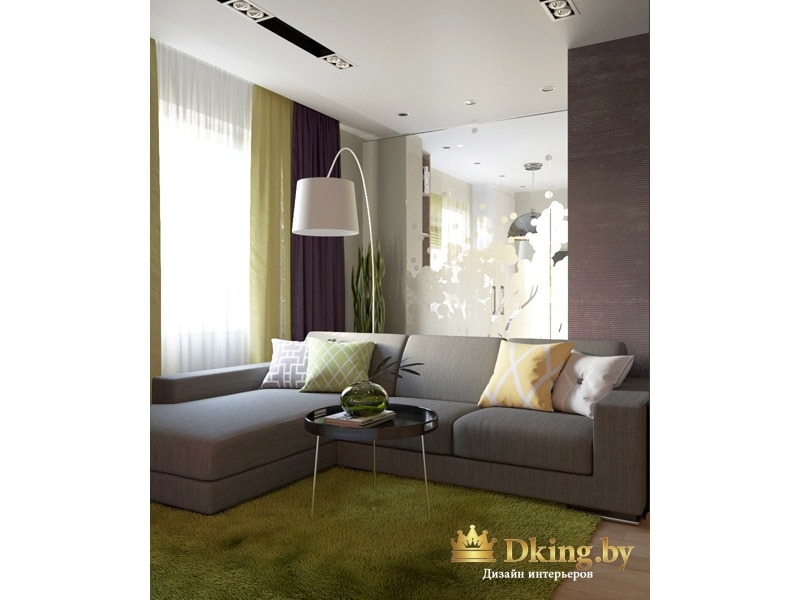 серый угловой диван с простыми формами. на полу ковер, по фактуре и цвету напоминающиу траву. В углу большой белый торшер. Потолок белый, одноуровневый